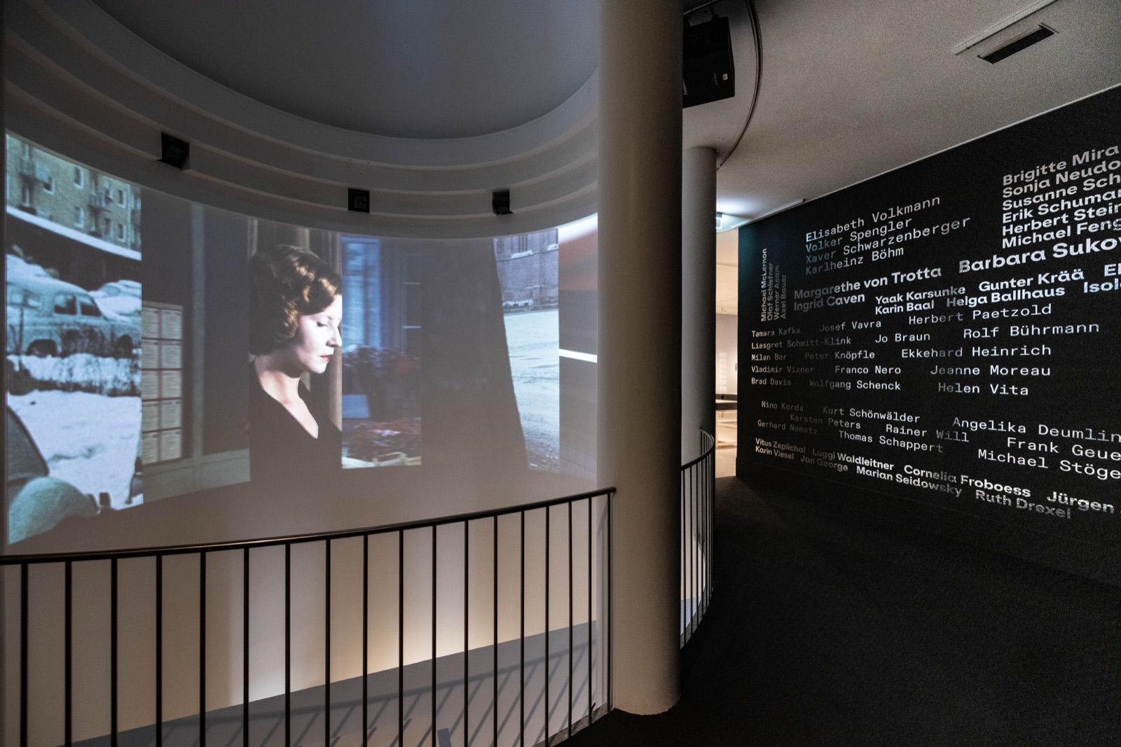 Der Rundsaal von der Seite, mit einer Projektion und einer dunklen Wand voller Namen in heller Schrift